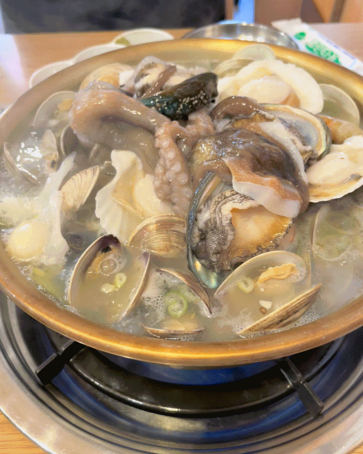 Olla llena de mariscos hirviendo sobre un hornillo de gas