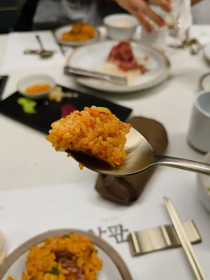 Un boccone di riso fritto con condimento rosso su un cucchiaio